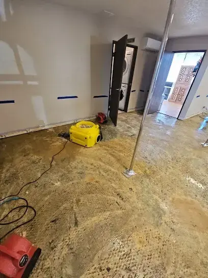 Air mover on a stripped floor in an empty room with the doors open