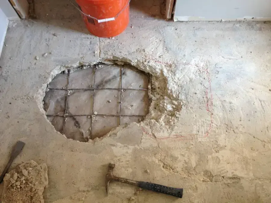 Hole broken through a concrete floor slab to reach a leaking pipe in a Fountain Valley home